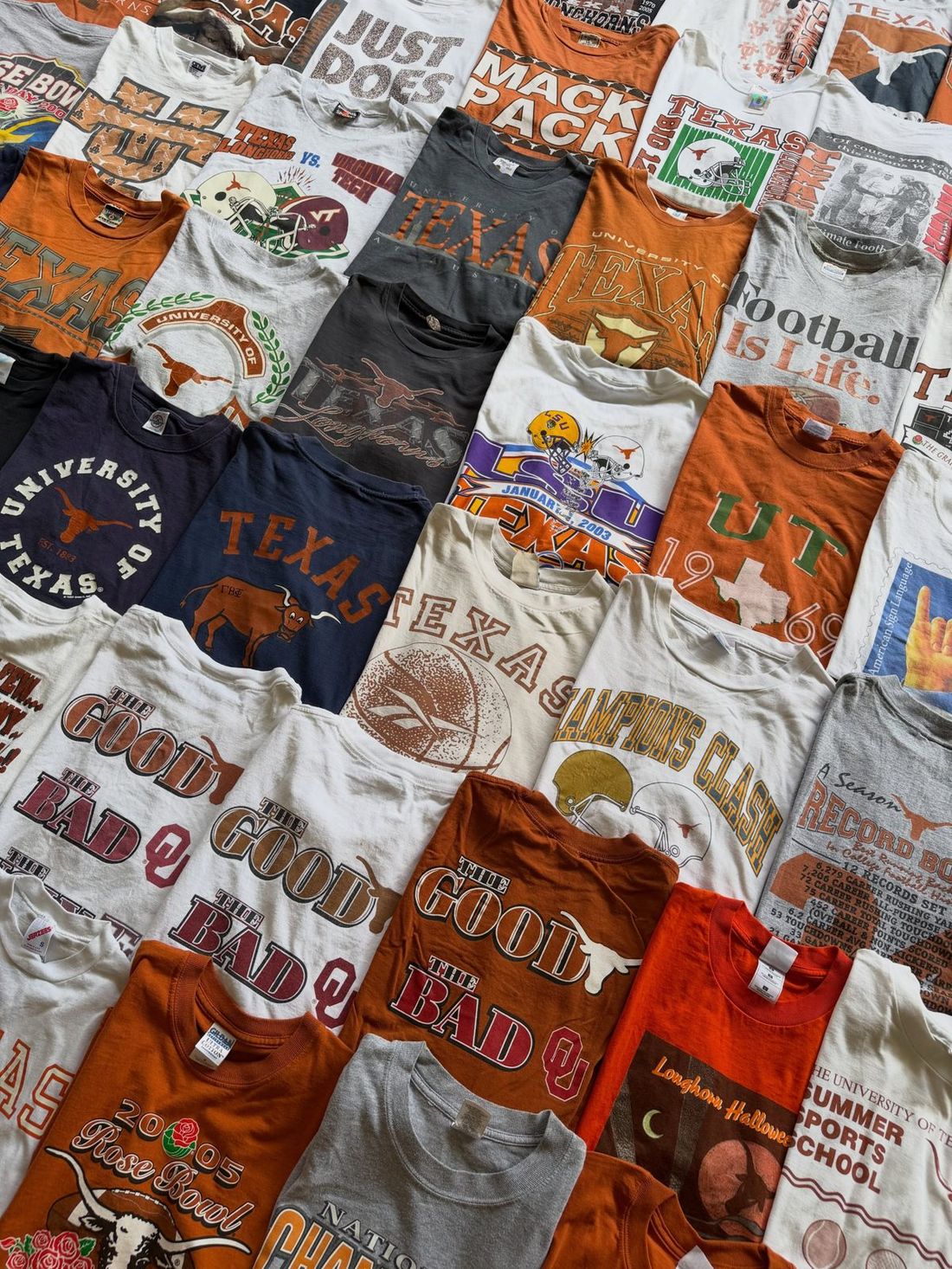 Stacks of vintage Longhorns and college football tees laid out on concrete